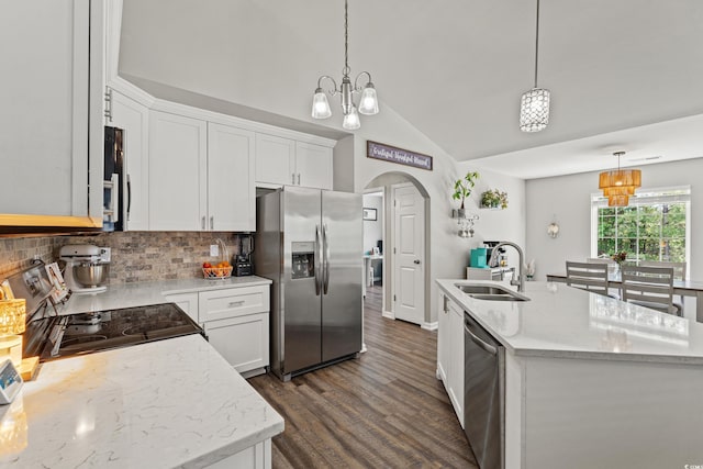 kitchen with appliances with stainless steel finishes, a sink, arched walkways, a chandelier, and tasteful backsplash