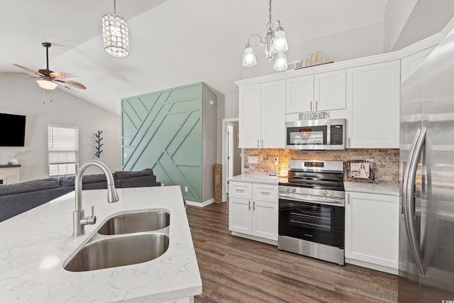 kitchen with appliances with stainless steel finishes, vaulted ceiling, a sink, ceiling fan with notable chandelier, and open floor plan