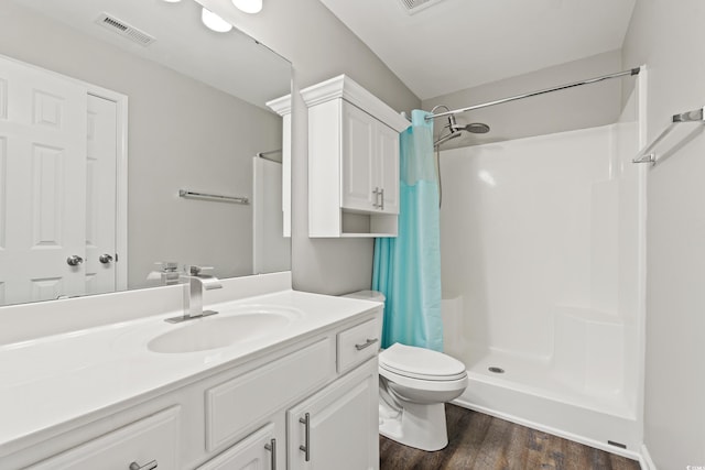 bathroom featuring visible vents, vanity, wood finished floors, toilet, and a stall shower