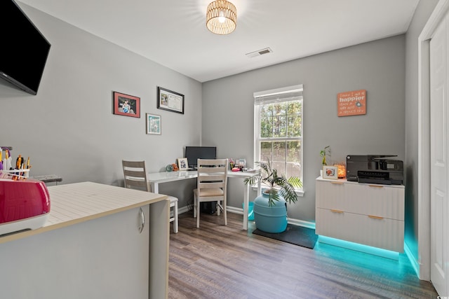 office space with baseboards, visible vents, and wood finished floors
