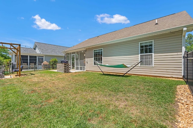 rear view of property with a lawn, fence, and a sunroom