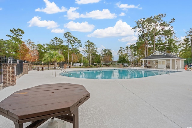 pool with a patio area and fence