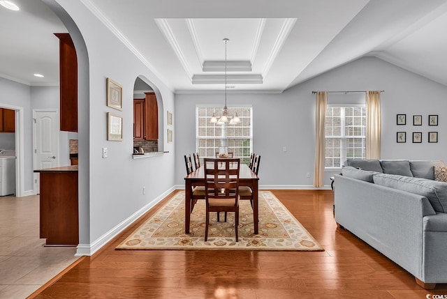 dining room with an inviting chandelier, arched walkways, crown molding, and light wood-type flooring