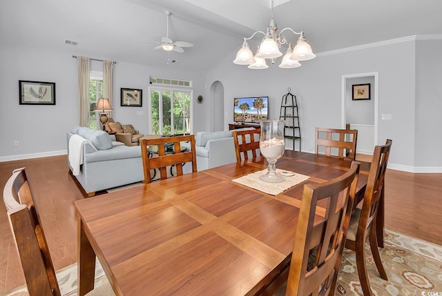 dining area featuring arched walkways, ceiling fan with notable chandelier, wood finished floors, lofted ceiling, and visible vents
