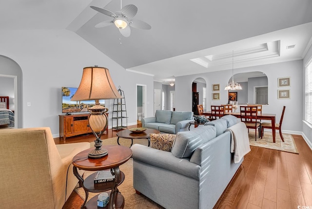 living area featuring visible vents, arched walkways, wood finished floors, baseboards, and ceiling fan with notable chandelier
