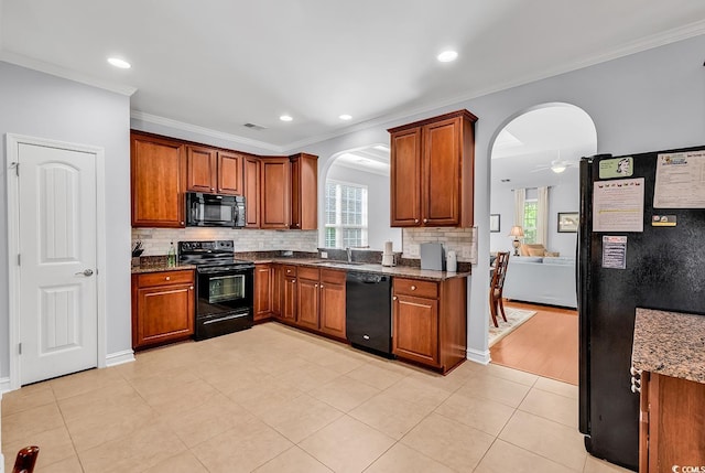 kitchen featuring plenty of natural light, arched walkways, a sink, and black appliances