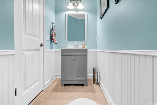 bathroom with vanity, a wainscoted wall, tile patterned flooring, and a decorative wall