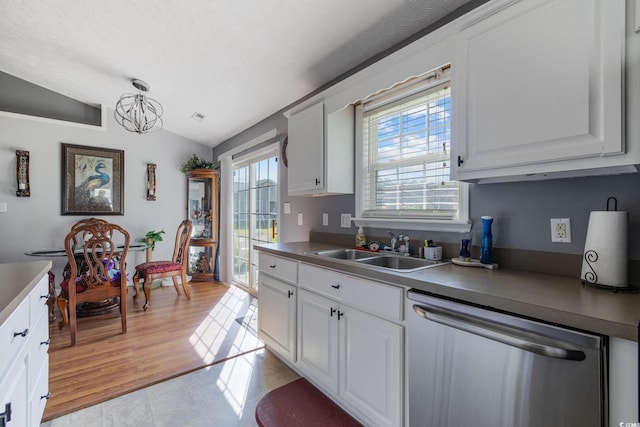 kitchen with stainless steel dishwasher, a sink, vaulted ceiling, a chandelier, and white cabinetry