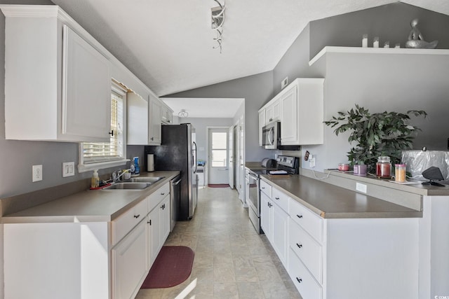 kitchen featuring stainless steel appliances, a sink, lofted ceiling, and white cabinets
