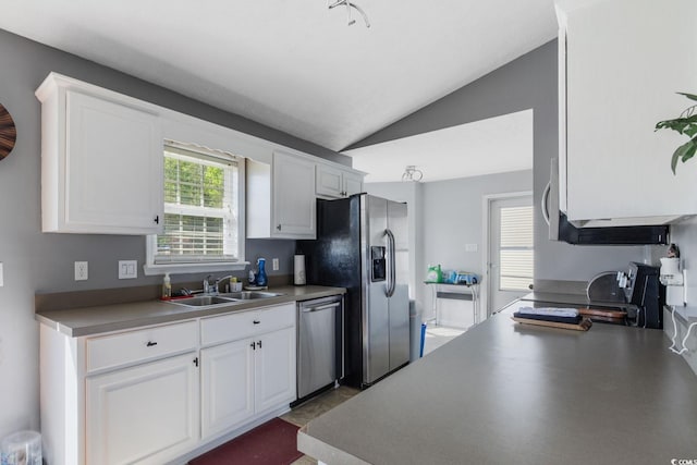 kitchen featuring stainless steel appliances, white cabinets, lofted ceiling, and a sink