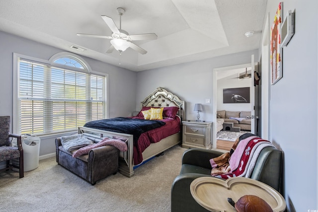 carpeted bedroom with a raised ceiling, a ceiling fan, and baseboards