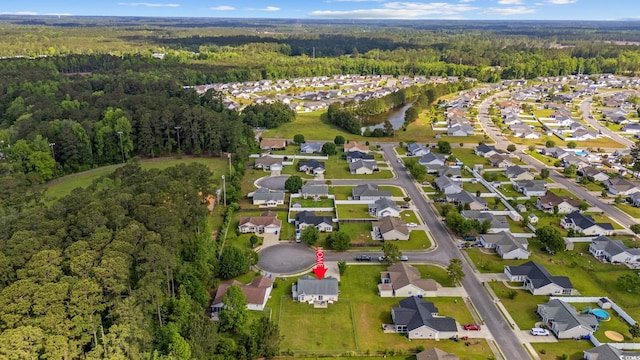aerial view of property and surrounding area with a forest and nearby suburban area