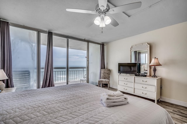 bedroom featuring baseboards, multiple windows, wood finished floors, and access to exterior