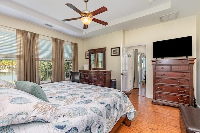 2940 Tigers Eye Rd, Little River, SC 29566 - bedroom featuring a tray ceiling, light wood-style floors, ceiling fan, and baseboards