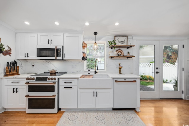 kitchen with light wood finished floors, a sink, white appliances, white cabinets, and backsplash