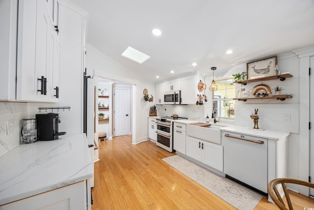 kitchen featuring light wood-style floors, white cabinetry, lofted ceiling with skylight, and white appliances