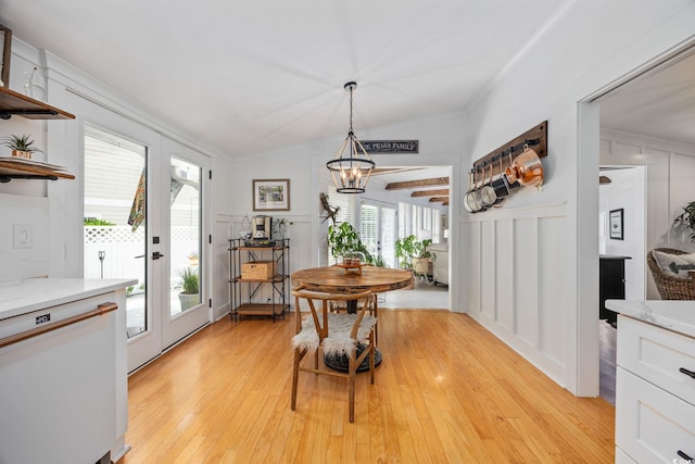 dining space with ornamental molding, a healthy amount of sunlight, a chandelier, and a decorative wall