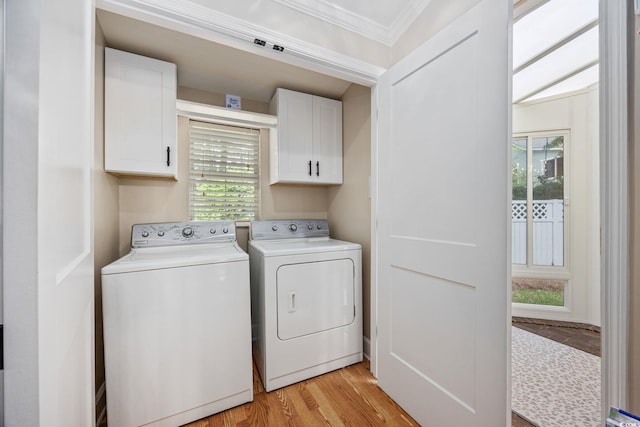 clothes washing area with a wealth of natural light, ornamental molding, light wood finished floors, washing machine and clothes dryer, and cabinet space