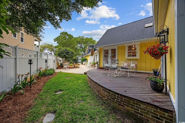 view of yard featuring a wooden deck, french doors, and fence