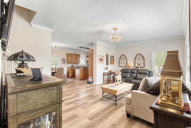 living room with an inviting chandelier, baseboards, ornamental molding, and light wood finished floors