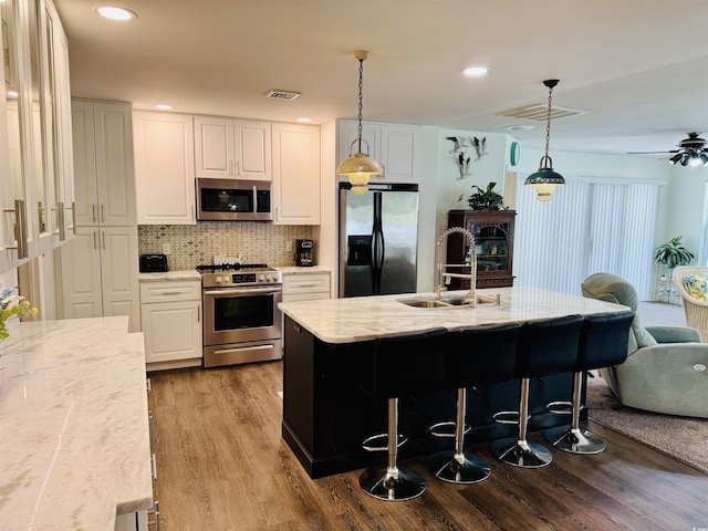 801 Talbot Cir, Myrtle Beach, SC 29577 - kitchen featuring stainless steel appliances, a sink, wood finished floors, light stone countertops, and white cabinetry