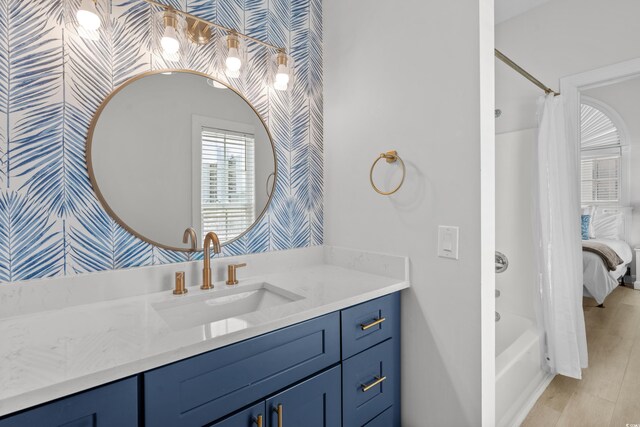 full bath featuring vanity, shower / tub combo, and wallpapered walls