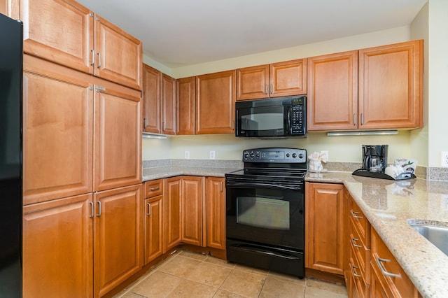 8121 Amalfi Pl Unit 4-801, Myrtle Beach, SC 29572 - kitchen featuring black appliances, light tile patterned floors, light stone counters, and brown cabinetry