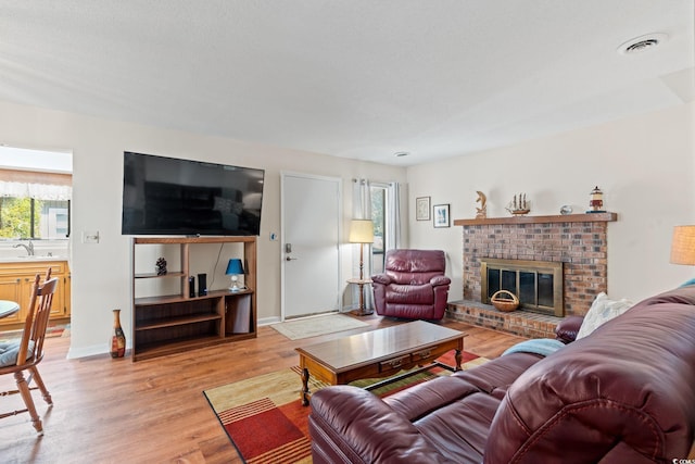 living area with visible vents, light wood-style flooring, and a fireplace