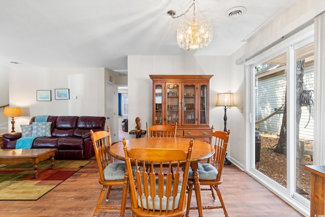 dining area featuring visible vents, light wood-style flooring, and a chandelier