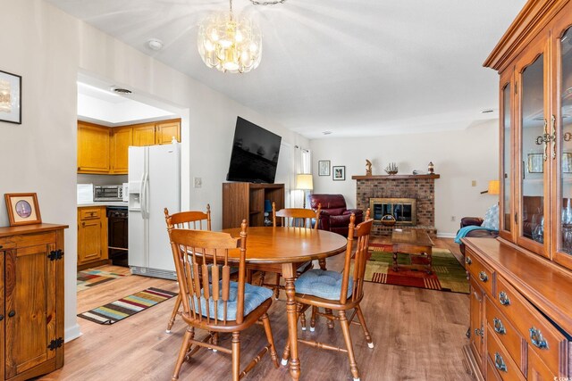 607A 28th Ave S, North Myrtle Beach, SC 29582 - dining room featuring light wood finished floors, a fireplace, and a chandelier