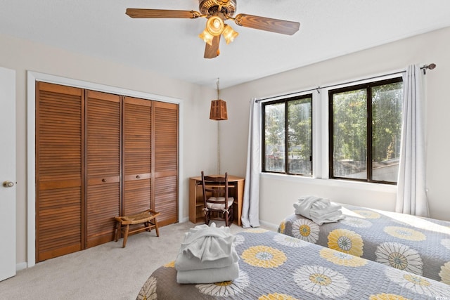 bedroom featuring a closet, a ceiling fan, baseboards, and light colored carpet