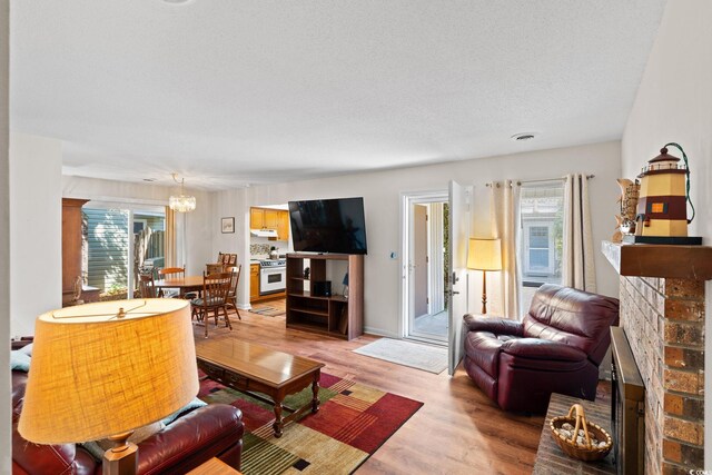607A 28th Ave S, North Myrtle Beach, SC 29582 - living room with a fireplace, plenty of natural light, light wood-style floors, a chandelier, and a textured ceiling