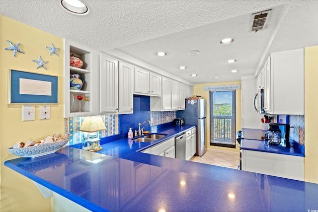 kitchen featuring dark countertops, a sink, stainless steel appliances, backsplash, and visible vents