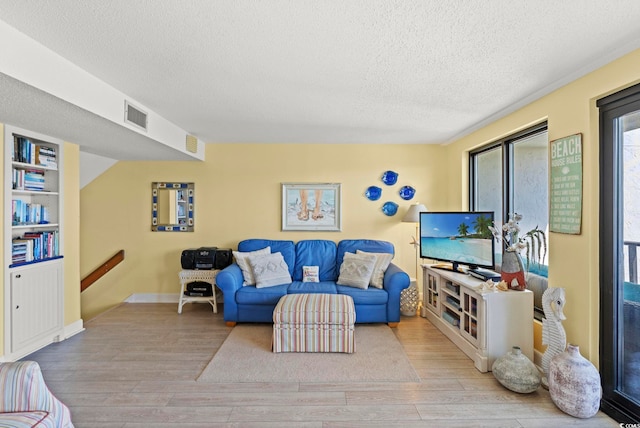 living room featuring visible vents, a textured ceiling, and wood finished floors