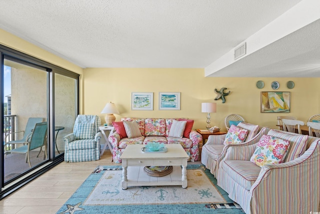 living room with a textured ceiling, wood finished floors, and visible vents