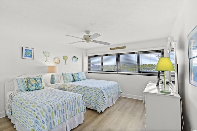bedroom with baseboards, ceiling fan, and light wood-style flooring