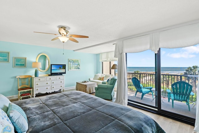 bedroom with multiple windows, a ceiling fan, wood finished floors, and access to exterior