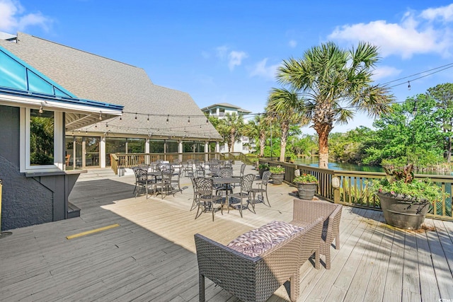 wooden deck with a water view and outdoor dining area