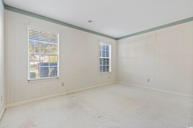 spare room with carpet floors, baseboards, and visible vents