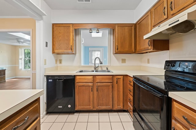kitchen featuring under cabinet range hood, light countertops, black appliances, and a sink