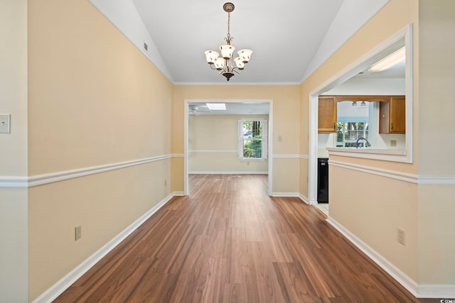 hall with vaulted ceiling, wood finished floors, baseboards, and a notable chandelier