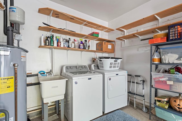 clothes washing area with washer and dryer, laundry area, gas water heater, and a sink