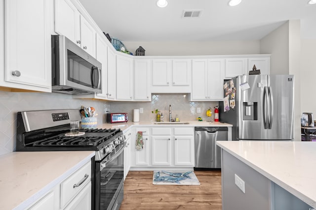1048 Longwood Bluffs Cir, Murrells Inlet, SC 29576 - kitchen featuring appliances with stainless steel finishes, a sink, white cabinetry, light wood finished floors, and light stone counters