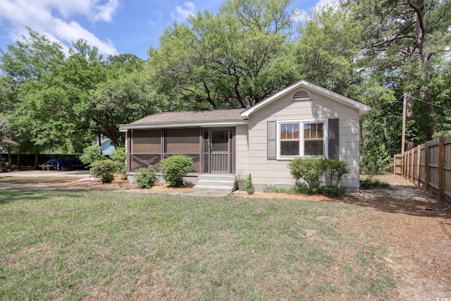 view of front of home with a sunroom, a front lawn, and fence