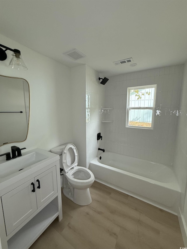 bathroom with shower / washtub combination, toilet, wood finished floors, and visible vents
