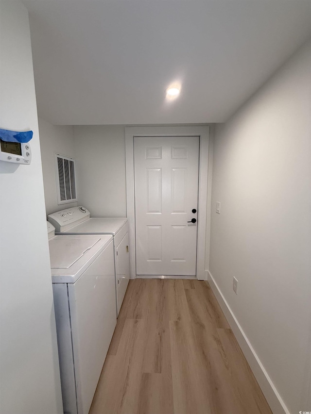 laundry room with laundry area, visible vents, washing machine and clothes dryer, light wood-style flooring, and baseboards