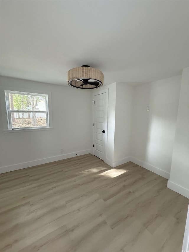 unfurnished room with baseboards and light wood-style flooring