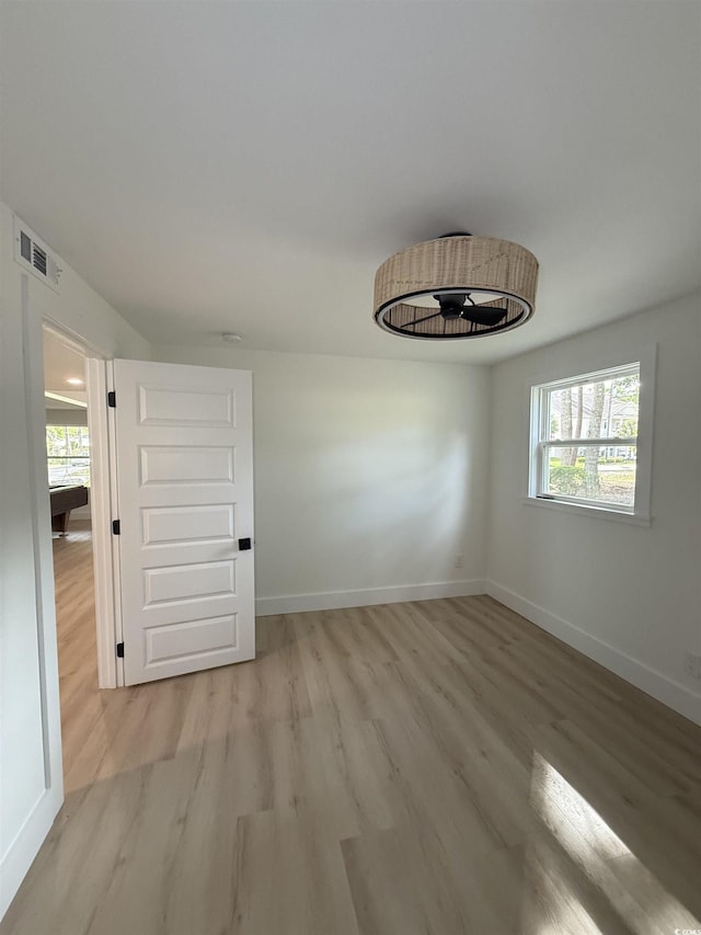 spare room featuring light wood-style floors, baseboards, and visible vents