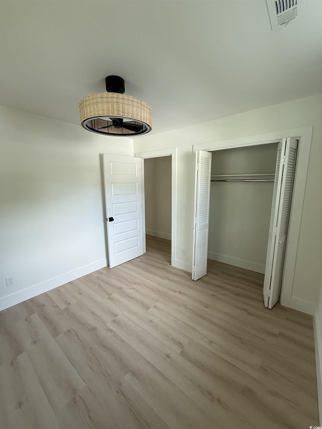 unfurnished bedroom featuring baseboards, a closet, wood finished floors, and visible vents