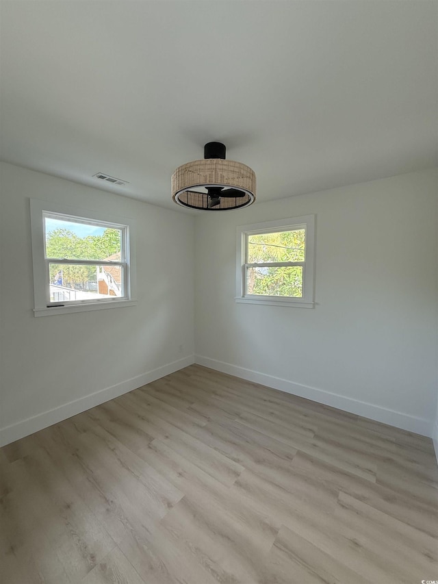 unfurnished room with light wood finished floors, baseboards, and visible vents